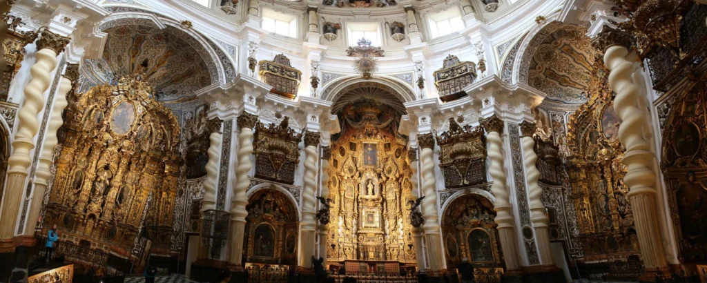 Interior barroco de la Iglesia de San Luis de los Franceses en Sevilla con retablo dorado y columnas salomónicas.