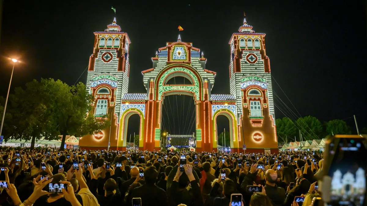 Alumbrado de la Feria de Abril de Sevilla 2025 con la portada iluminada y público