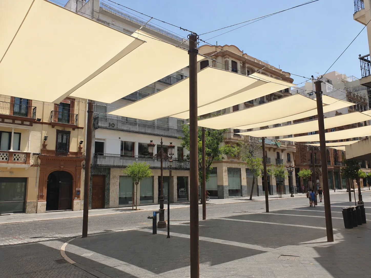 na terraza sevillana con toldo o una calle estrecha con toldos tradicionales dando sombra.